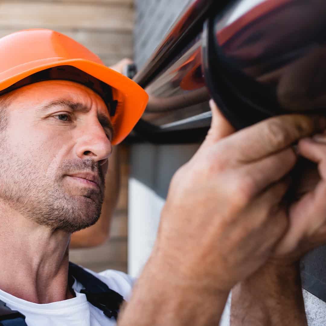 Selective focus of builder working with rain gutter on facade of building